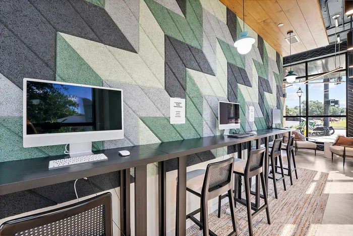 Modern co-working space with sleek computer stations against a trendy geometric wall design, offering a vibrant and productive atmosphere.