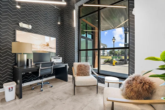 Chic and modern home office with stylish decor, featuring a sleek desk, comfortable seating, and large window with bright outdoor view.