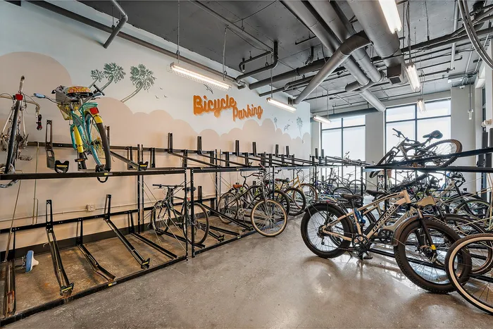 Modern bike storage room featuring well-organized racks with various bicycles, set in a bright, industrial-style space with artistic wall designs.