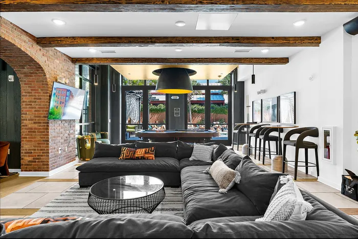 Modern and inviting lounge area with plush seating, brick accent walls, and expansive windows overlooking a vibrant outdoor pool area.