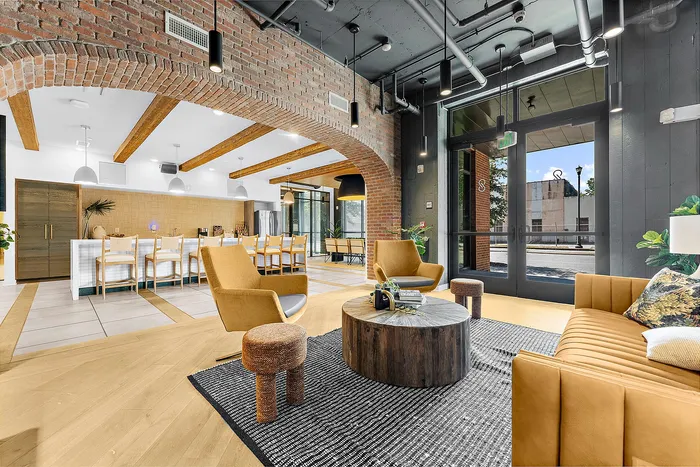 Modern apartment lounge with exposed brick, stylish furnishings, and a cozy seating area.