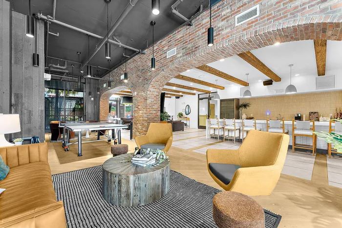 Chic industrial-style lounge with exposed brick, modern furnishings, and a sleek pool table.