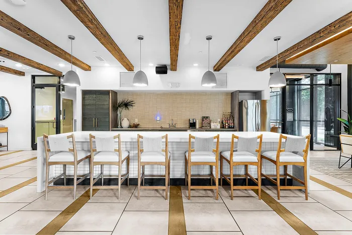 Modern communal kitchen with sleek countertops, stylish bar seating, and trendy pendant lights, perfect for social gatherings.
