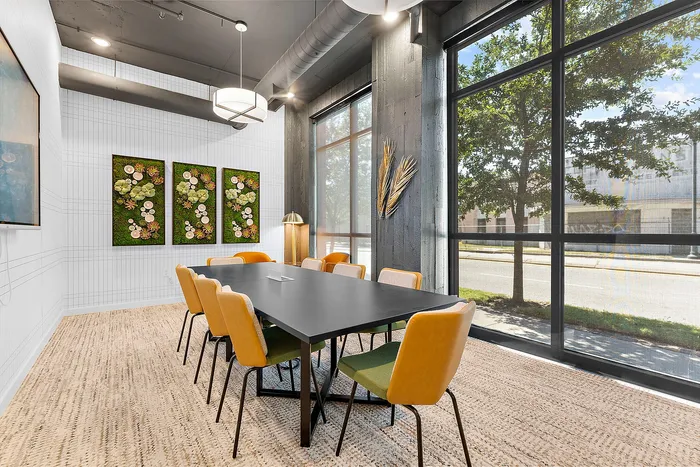 Chic conference room with modern black table, vibrant yellow chairs, and large windows offering a natural view.