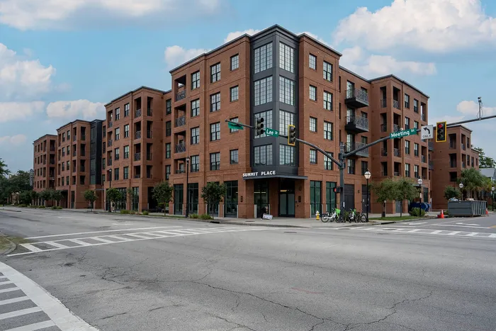 Modern urban apartment building with stylish brick facade at a city intersection, offering spacious living with convenient amenities.