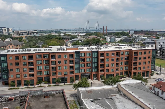 Modern urban residential building with stylish brick facade located in a vibrant neighborhood with scenic views of a large bridge and a beautiful sky.