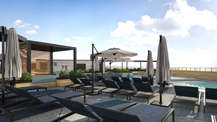 Luxurious rooftop pool area featuring stylish lounge chairs, shaded cabanas, and panoramic views under a bright blue sky.