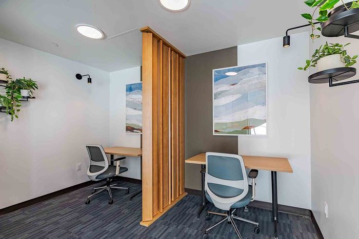 Modern study space with dual workstations, stylish wooden divider, and vibrant artwork, perfect for productivity and creativity.