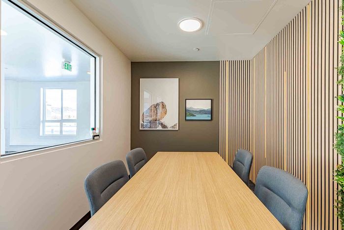 Bright and modern meeting room featuring a wooden table, sleek chairs, and stylish wall art, perfect for productive gatherings.