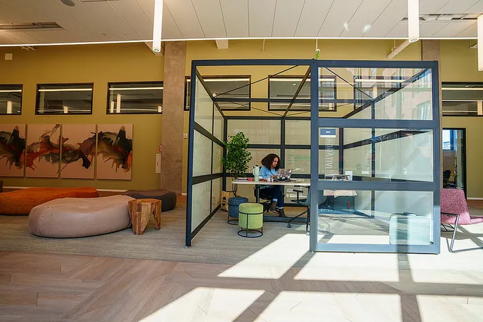 Modern office space with glass-walled meeting area and artistic decor.