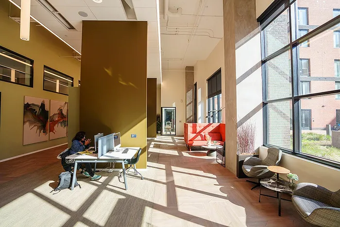 Contemporary office space with vibrant artwork, large windows, and comfortable seating area.