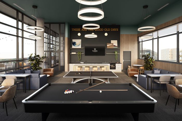 Modern communal lounge featuring a sleek billiards and ping pong table, cozy seating arrangements, and stylish lighting with expansive city views.