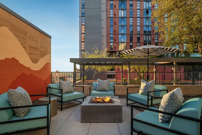 Modern outdoor patio with stylish seating, vibrant mural, and cozy fire pit, perfect for relaxation and entertaining.