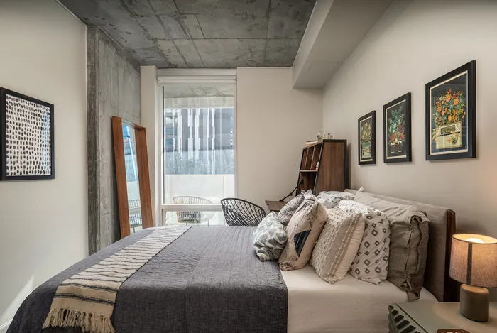 Modern bedroom with elegant decor, featuring a stylish bed, cozy pillows, and large window with abundant natural light.