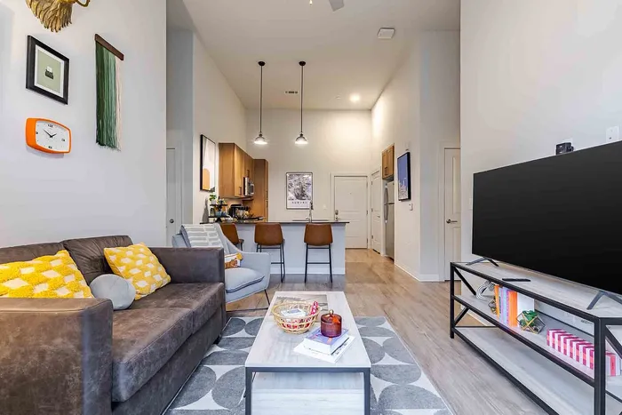 Contemporary open-plan living room with cozy brown sofa, vibrant decor, and modern kitchen adjacent, ideal for relaxation and entertaining.