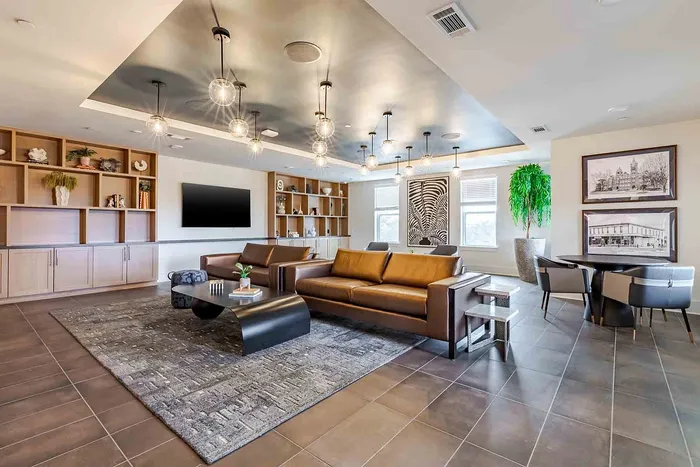 Luxurious open-concept living space with contemporary lighting, elegant leather sofas, and sophisticated shelving, perfect for stylish gatherings.