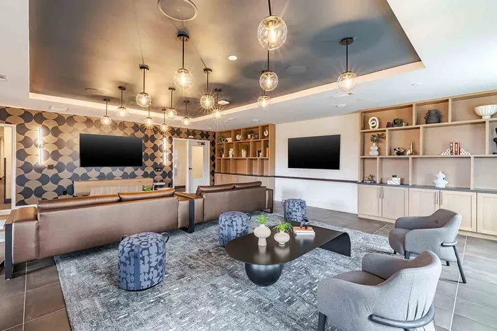 Modern living room with stylish geometric wallpaper, elegant lighting fixtures, and cozy seating arrangement.
