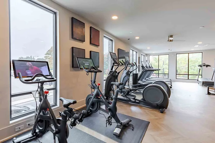 Modern fitness center with state-of-the-art exercise bikes and treadmills, offering a bright and inviting workout space with large windows.