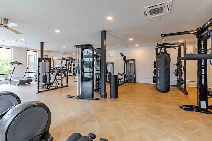 Spacious and modern fitness center featuring state-of-the-art gym equipment, sleek hardwood floors, and ample natural light.