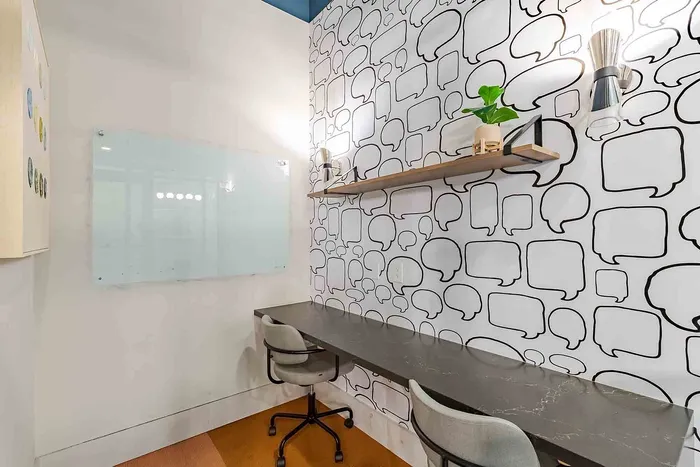Modern workspace featuring a sleek marble desk, stylish chairs, and a vibrant wall with creative speech bubble patterns. Ideal for productivity and inspiration.