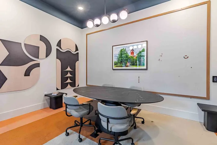 Sleek modern meeting room with abstract wall art, elegant black table, and plush grey chairs, perfect for creative collaboration.