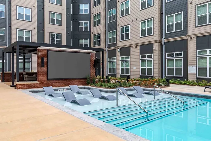 Modern apartment complex with inviting pool featuring comfortable lounge chairs and a stylish outdoor entertainment area.