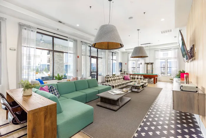 A clubhouse with lounge chairs, couches, a pool table, and a flatscreen television at Domain at Town Centre apartments in Morgantown, WV