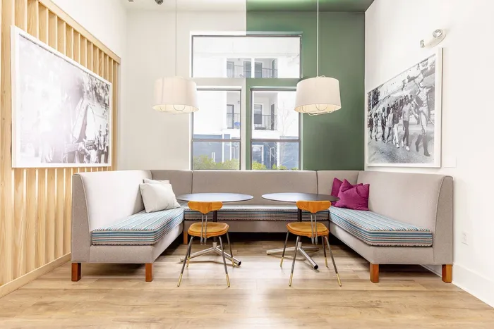 Lounge space at our apartments in Morgantown, featuring booth seating, tables, and a large window facing the apartment complex.