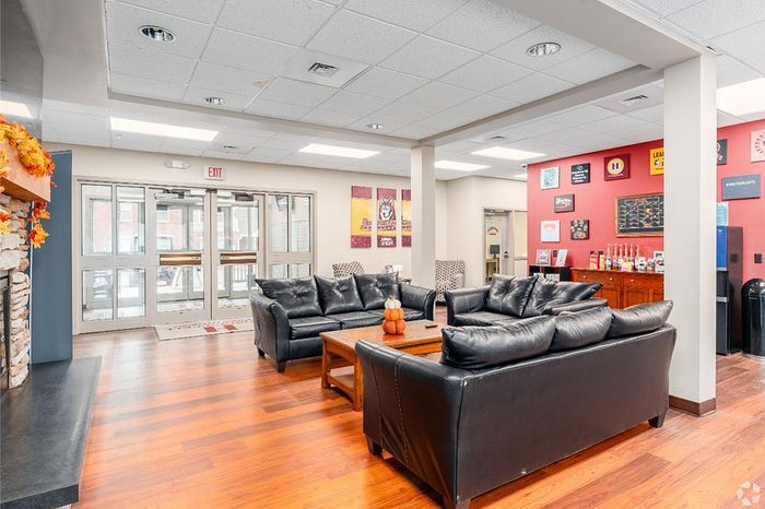 Inviting community lounge with plush leather sofas, modern decor, and vibrant wall art, perfect for relaxation and social gatherings.