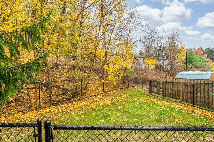 Charming backyard with lush green grass, vibrant autumn leaves, and a scenic wooded backdrop, perfect for relaxation.