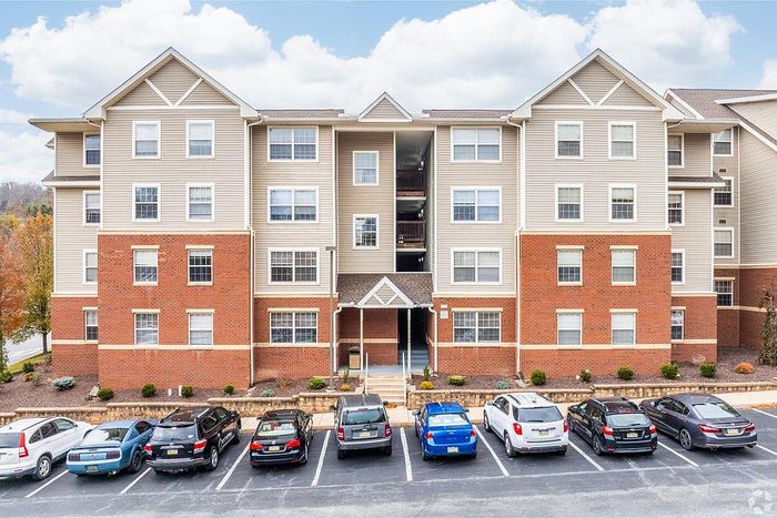 Beautiful multi-story apartment building with modern brick and siding design, ample parking, and well-maintained landscaping.