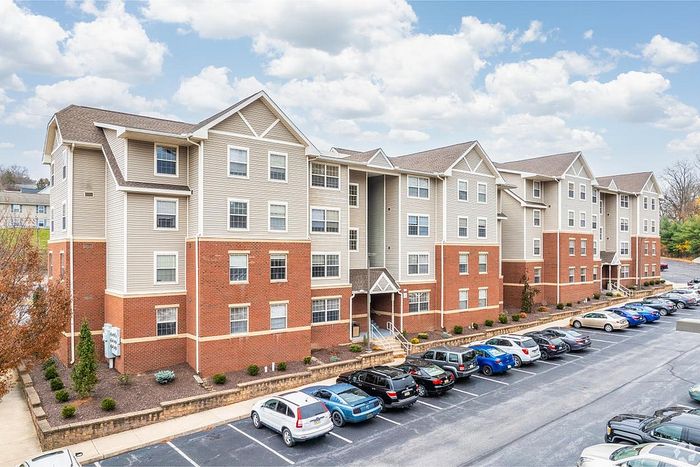 Modern multi-story apartment building with a charming brick facade, ample parking, and a beautifully landscaped exterior.