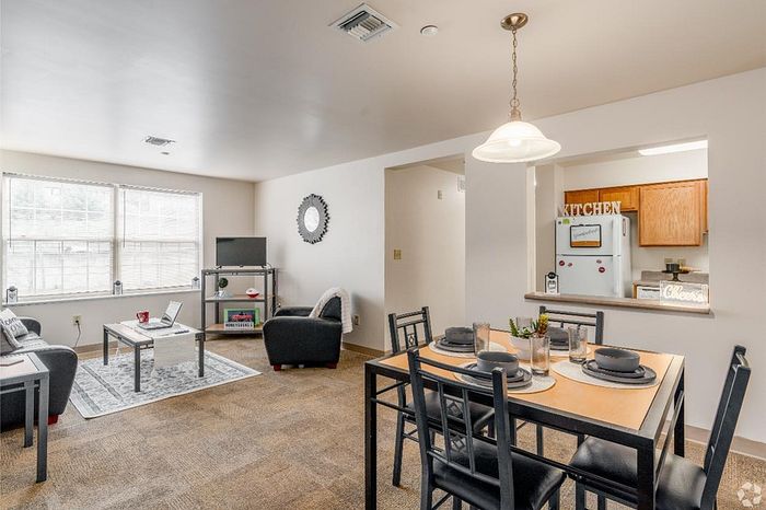 Bright and inviting living-dining area with modern furniture, ample natural light, and a stylish kitchen pass-through in an elegant apartment.