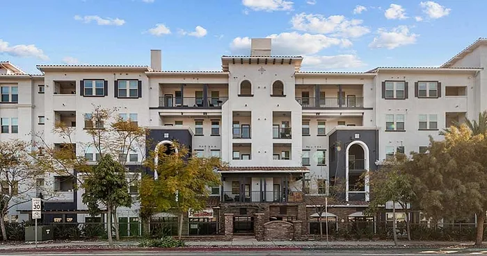 Charming modern apartment complex with Mediterranean-inspired architecture, featuring arched windows, balconies, and lush landscaping.