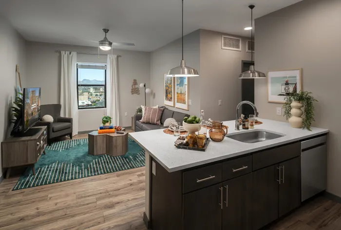 Chic modern living room with elegant kitchen island, featuring sleek decor, wooden flooring, and a scenic city view through a large window.
