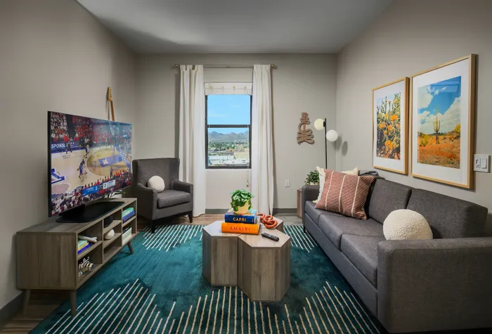 Chic living room with a modern gray sofa, elegant armchair, and vibrant decor, offering a stunning mountain view through a large window.