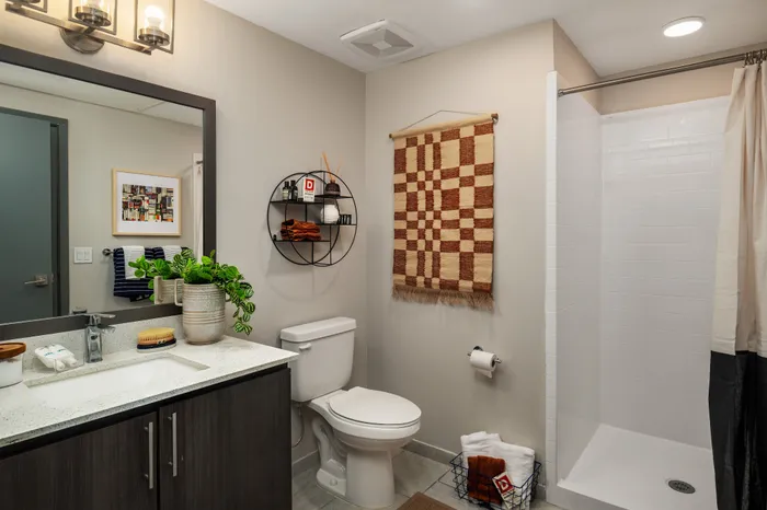 Modern bathroom with sleek vanity, potted plant accents, and a walk-in shower, exuding contemporary elegance.
