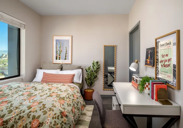 Cozy bedroom with a scenic view, featuring a floral duvet, stylish desk, and vibrant wall art.