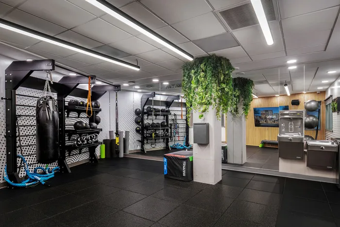 Modern gym featuring sleek fitness equipment, vibrant greenery, and ample workout space.