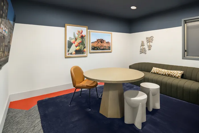 Chic modern lounge area with stylish decor, featuring a round wooden table, a cozy green sofa, and vibrant wall art.