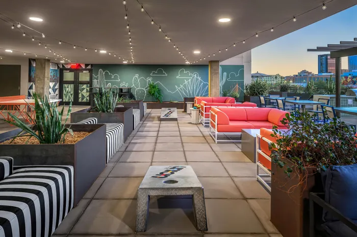 Vibrant rooftop lounge with chic seating, string lights, and cityscape views, perfect for relaxation and entertainment.