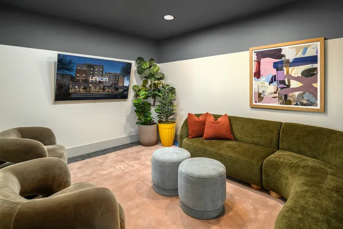 Modern living room with stylish olive green velvet sofa, abstract artwork, and vibrant plants creating a cozy, inviting atmosphere.
