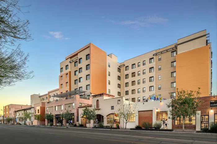 Modern apartment complex with stylish architecture, featuring a blend of vibrant colors and contemporary design, situated in a lively urban setting.