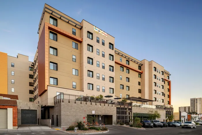 Modern urban apartment building with stylish facade and ample windows, showcasing a welcoming entrance and serene rooftop patio.
