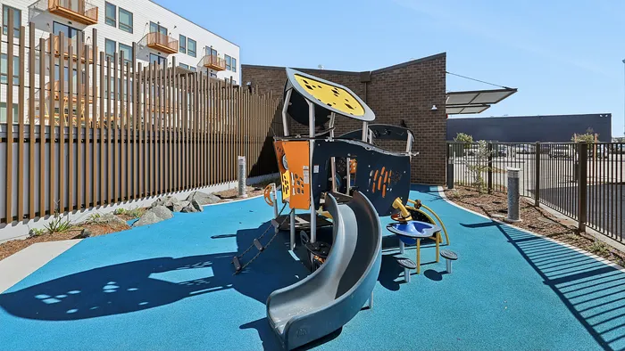 Inviting outdoor play area featuring a modern playground structure with a slide, located in a sunlit residential community.
