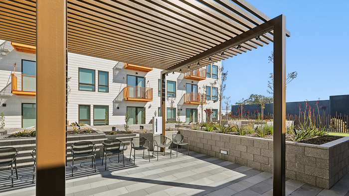 Modern apartment complex exterior showcasing stylish balconies and a landscaped patio area, perfect for relaxation.