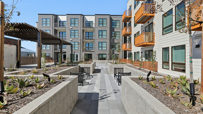 Modern urban apartment complex with stylish facades, vibrant balconies, and lush landscaped courtyard.
