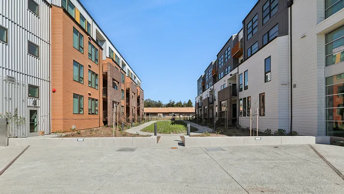 Modern apartment complex with sleek architectural design, featuring a landscaped courtyard and spacious walkways.