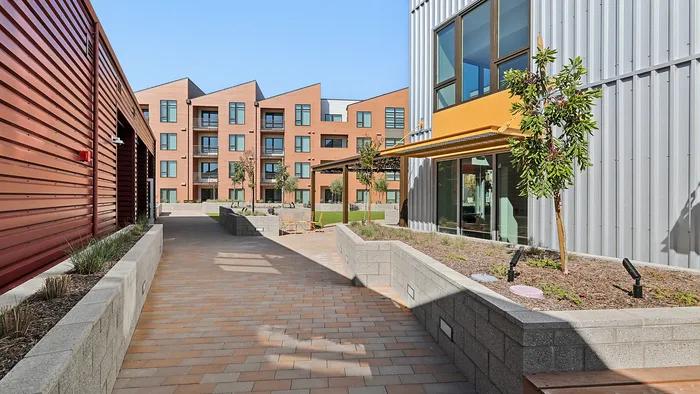 Modern apartment complex with a stylish exterior, featuring clean architectural lines, inviting pathways, and landscaped gardens.