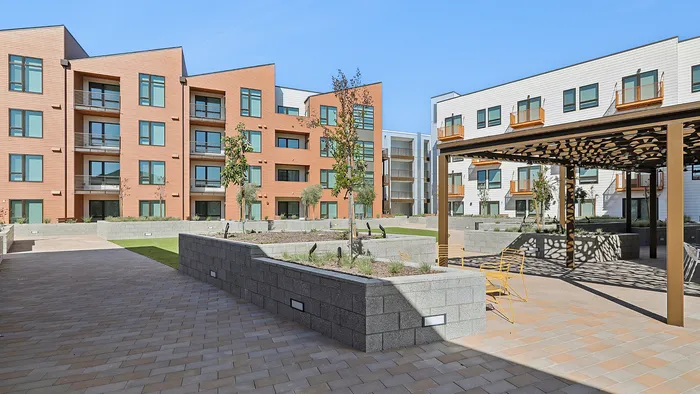 Modern apartment complex featuring landscaped courtyard, sleek architecture, and inviting outdoor seating.